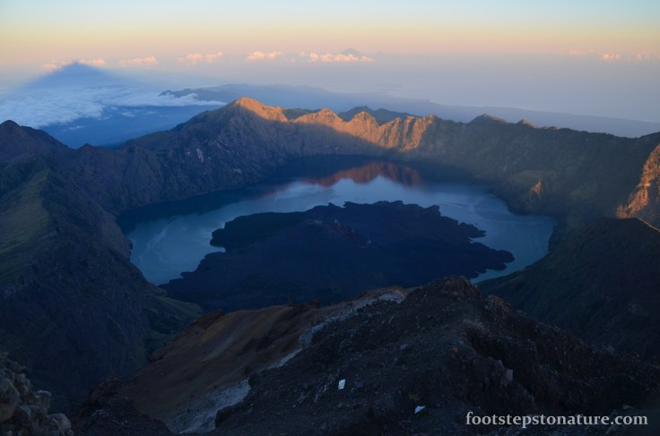 7.00am – The caldera rim and lake majestically illuminates as the sun rises. At the top left you’ll notice the shadow of Mt Rinjani’s peak and on the background you can also notice Mt. Agung of Bali